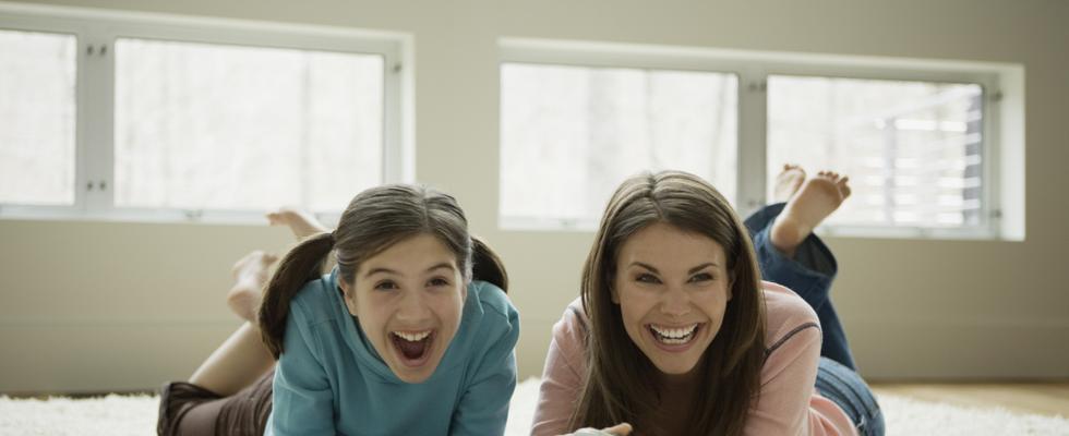 two girls smiling and lying in a floor